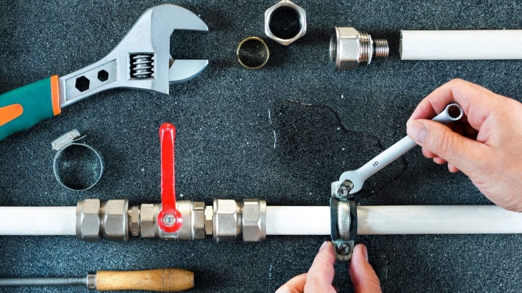 Plumber repairing a pipe valve with an adjustable wrench in Largo