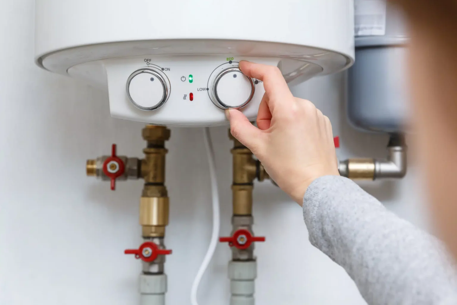 Homeowner adjusting the temperature controls on a water heater in Largo
